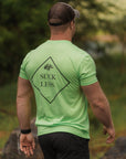 Man wearing a neon green t-shirt with 'Suck Less' text walking outdoors.