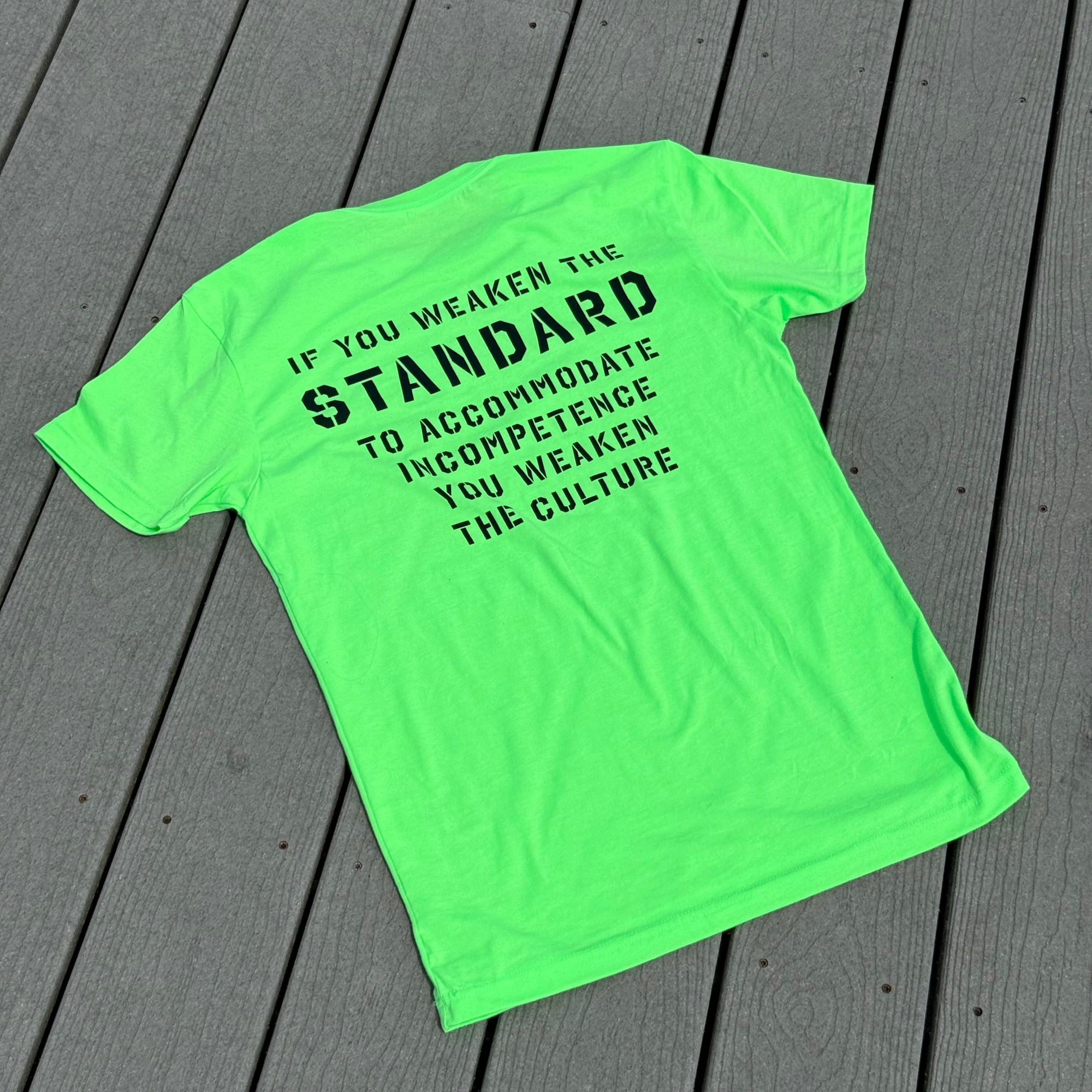 Neon green t-shirt with black text on a wooden surface