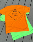 Orange t-shirt with 'Suck Less' text on a gray wooden surface
