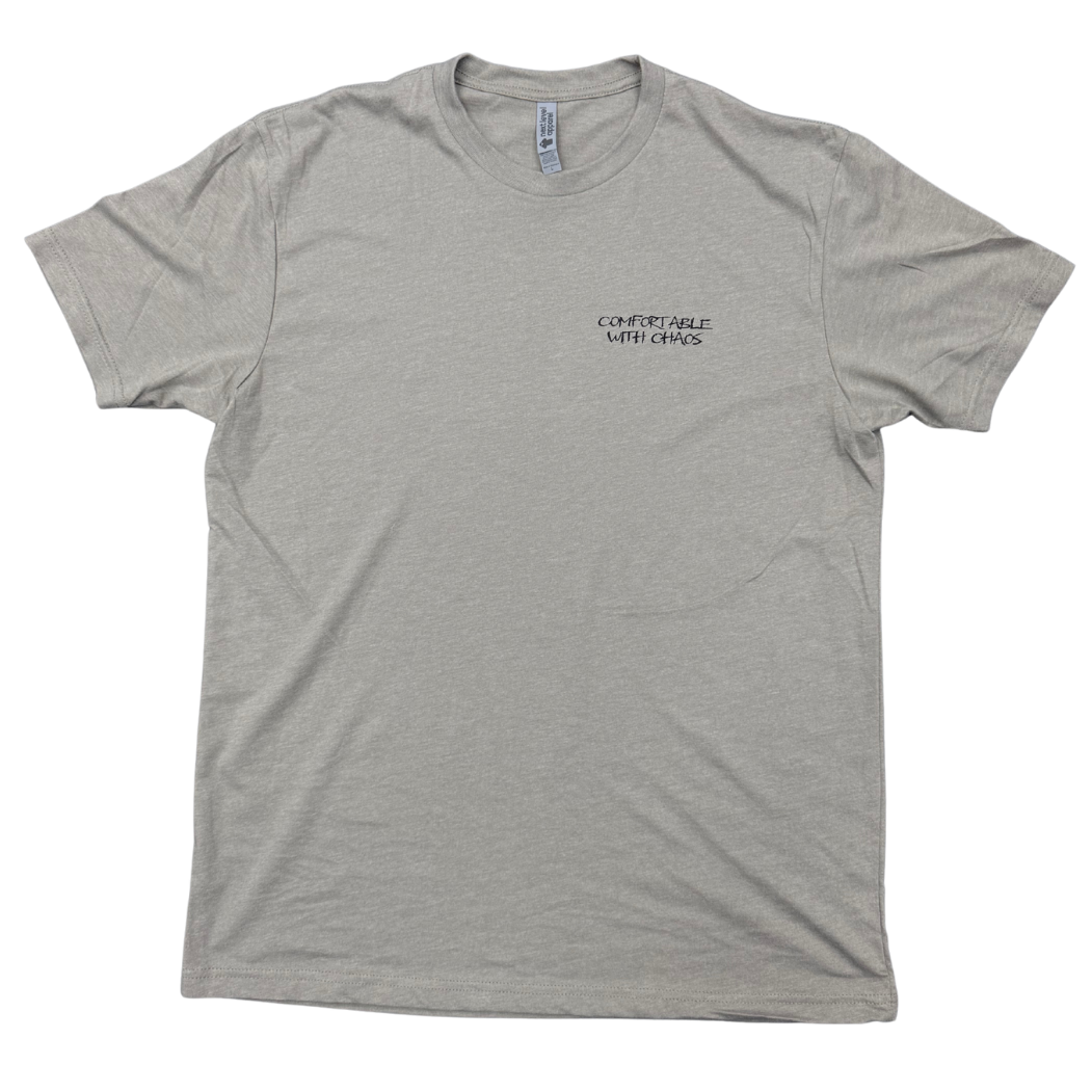 A stone gray crewneck t-shirt with a small black 'Comfortable with chaos' logo printed on the left chest, displayed flat against a white background.