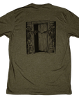 Green t-shirt with a graphic design of skeletons with rifles on a wooden door.