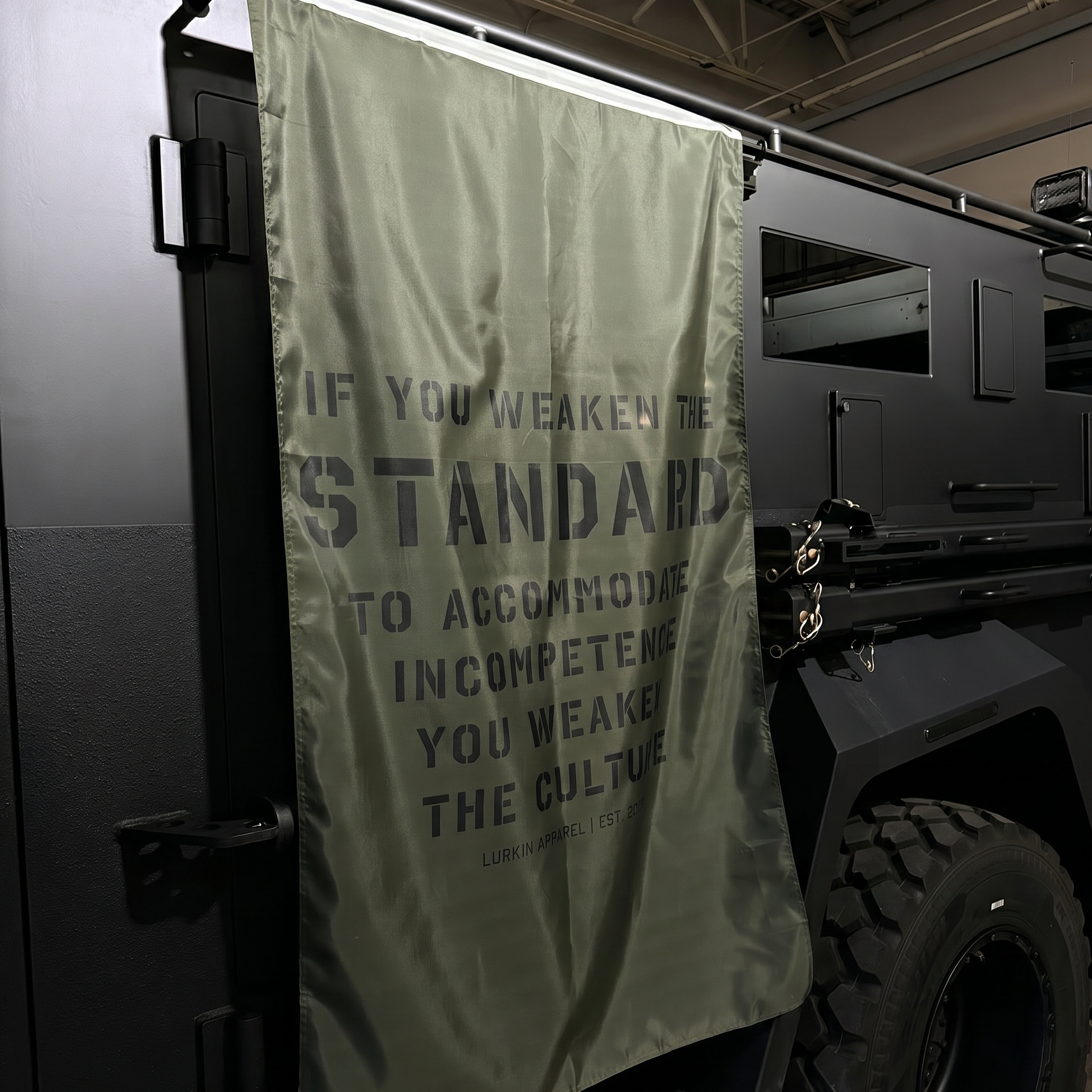 Dark-colored vehicle with a OD green flag displaying text inside a building.