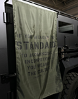 Dark-colored vehicle with a OD green flag displaying text inside a building.