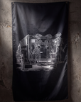 A black flag hanging on a textured concrete wall, featuring a white graphic illustration of skeleton figures standing beside a truck with the word 'LURKIN' on the side.
