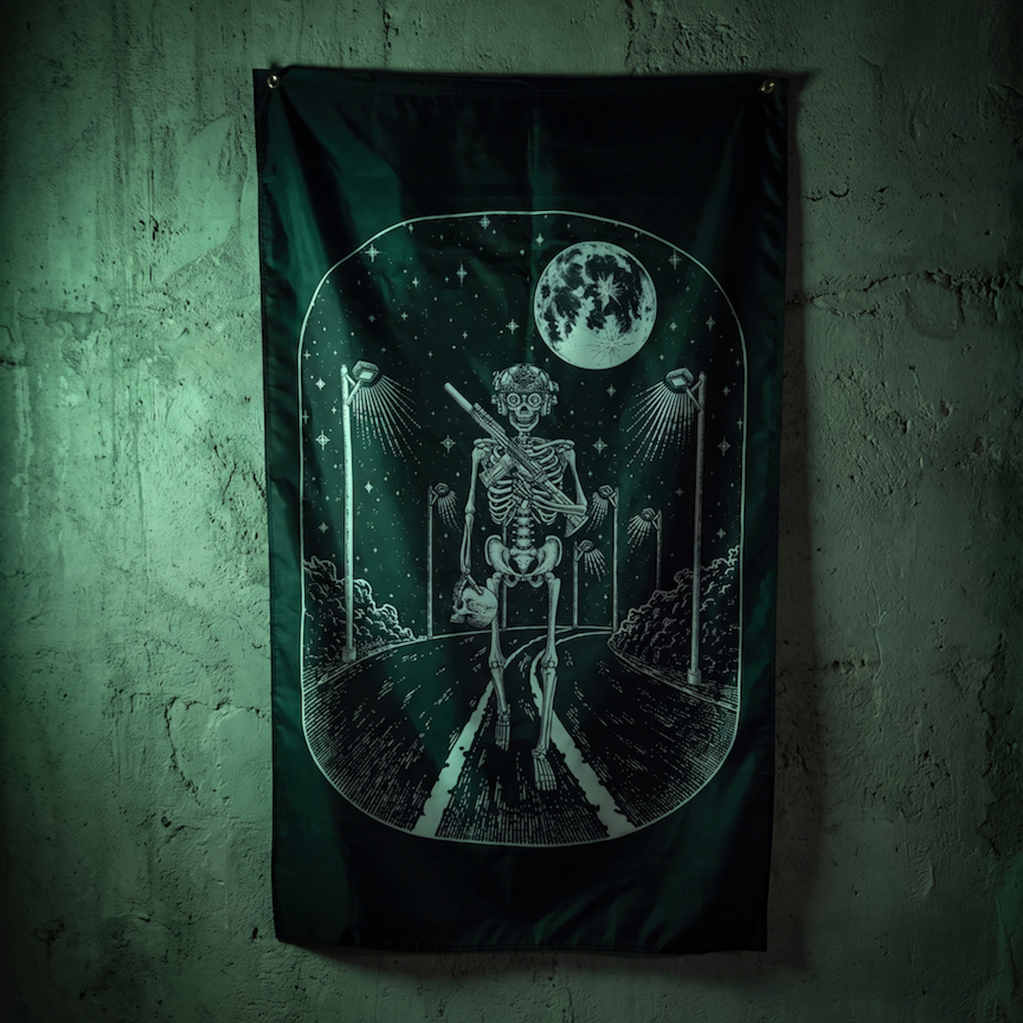 A dark gothic wall flag featuring a white skeleton walking on a road under a full moon, hung on a textured green wall.