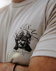Close-up of a person wearing a light beige t-shirt with a black graphic print of a helmeted figure.