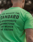 Person wearing a neon green t-shirt with a motivational message on the back, standing outdoors.
