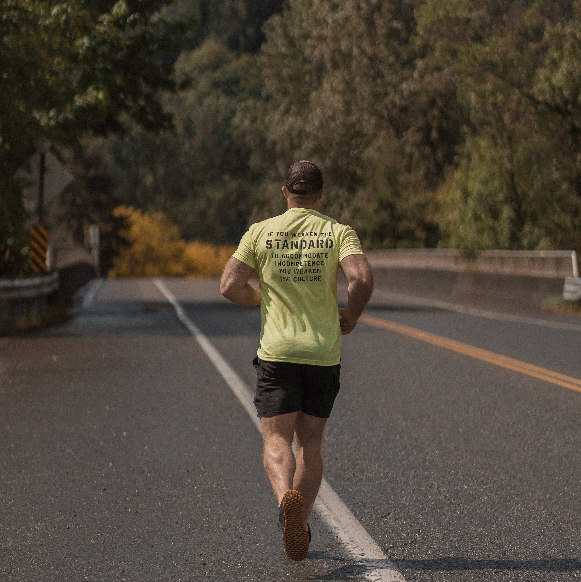 Person running on a road with trees and sky in the background