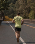Person running on a road with trees and sky in the background